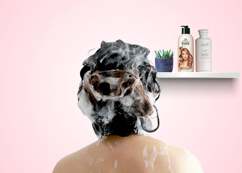 Woman with color-depositing shampoo applied on hair and a shelf on the wall highlighting the shampoo and a conditioner