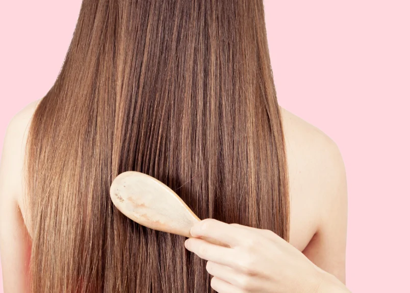 Woman getting her long, straight hair brushed with paddle brush