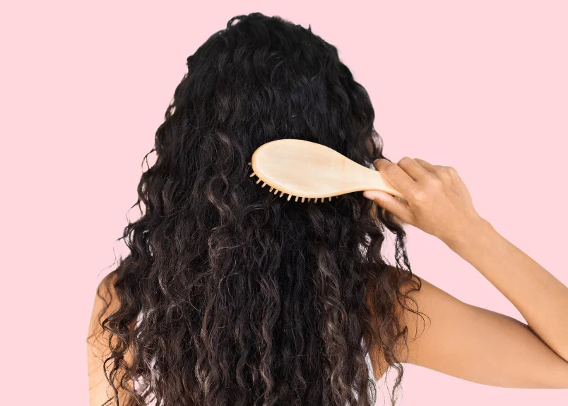 Woman with curly hair and bamboo hair brush