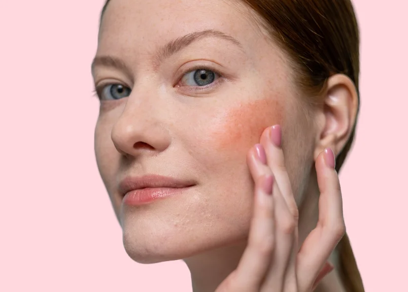 Woman applying lipstick as blush with finger 