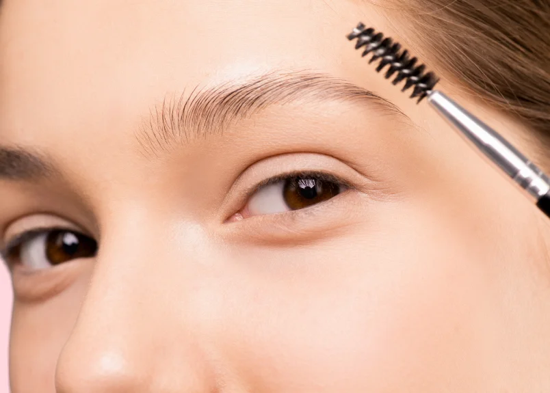 Woman applying clear macara on eyebrows