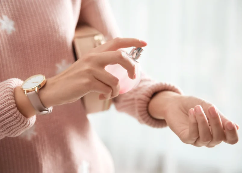 Woman spraying perfume on dress
